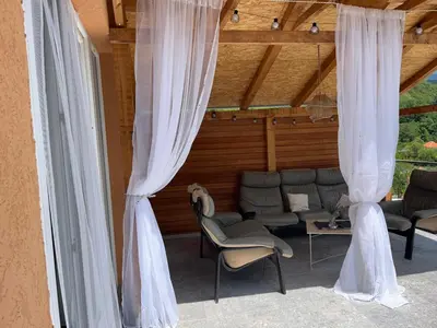 a patio with white curtains and chairs in a room at Apartmani Stankovic in Crni Vrh