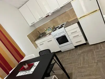 a kitchen with white cabinets and a table with a book at Apartmani Stankovic in Crni Vrh