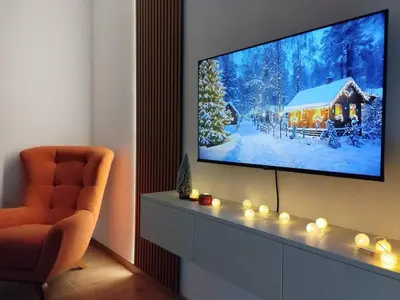 a living room with a tv and a chair at Merak stay 018 in Niš