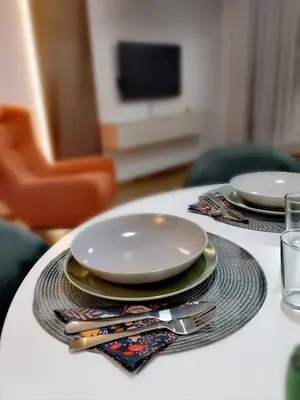 a table with plates and utensils on top of it at Merak stay 018 in Niš