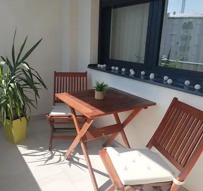 a wooden table and two chairs on a balcony at Merak stay 018 in Niš
