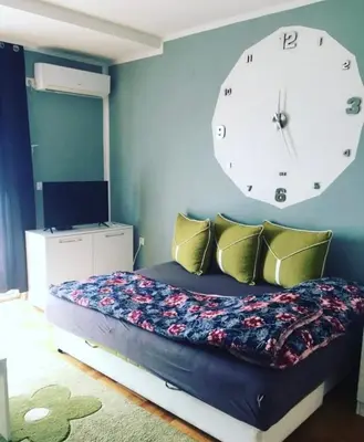 a bedroom with a bed with a large clock on the wall at Leon Apartman in Vrnjačka Banja