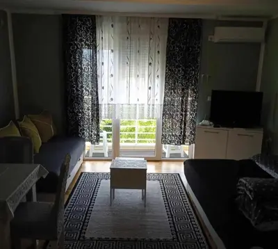 a living room with a couch and a table and a window at Leon Apartman in Vrnjačka Banja