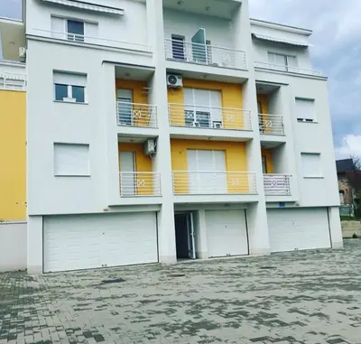 a white apartment building with two garages at Leon Apartman in Vrnjačka Banja