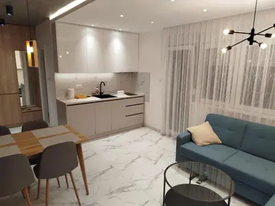 a living room with a blue couch and a kitchen at Vista MDD in Soko Banja