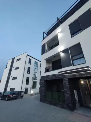 two buildings with a car parked in a parking lot at Apartman Jeca in Vrnjačka Banja