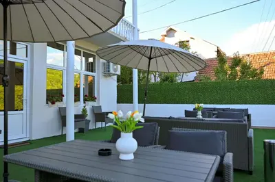 a patio with a table and chairs with umbrellas at Apartmani kod kumašina in Kuršumlija