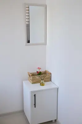 a white cabinet with a mirror and a basket on it at Apartmani kod kumašina in Kuršumlija