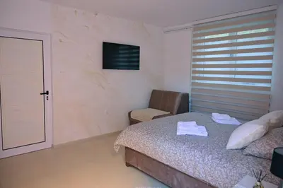 a bedroom with a bed and a chair and a television at Apartmani kod kumašina in Kuršumlija