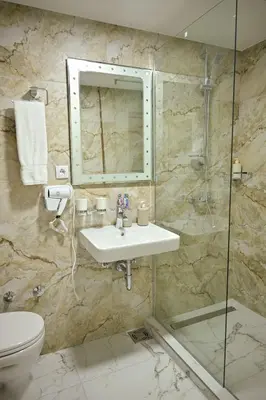 a bathroom with a sink and a shower and a toilet at Apartmani kod kumašina in Kuršumlija