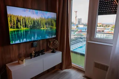 a living room with a tv and a large window at Harmonia Lux Aqua park in Jagodina