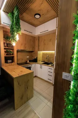 a kitchen with white cabinets and a wooden ceiling at Harmonia Lux Aqua park in Jagodina