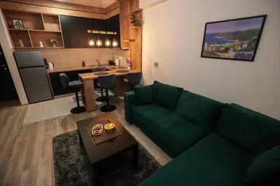 a living room with a green couch and a kitchen at Zeus Apartman in Jagodina