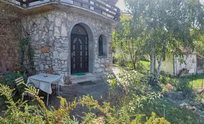 a stone building with a black door and a bench at Apartman Borići - nostalgija in Soko Banja