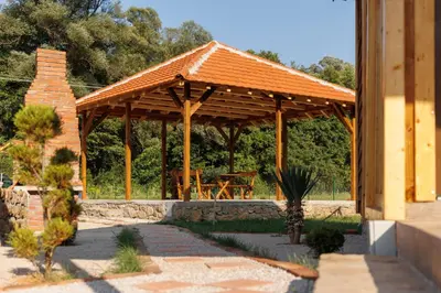 a wooden gazebo with a table in a garden at Brvnara Dadi