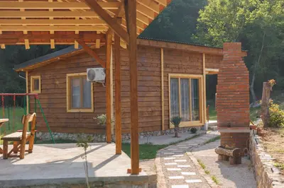 a log cabin with a porch and a brick pillar at Brvnara Dadi