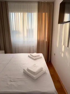 two towels on a bed in a room with a window at DarViva Apartment Niš, center, private garage parking, river view in Niš
