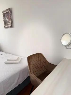 a room with a chair next to a bed at DarViva Apartment Niš, center, private garage parking, river view in Niš