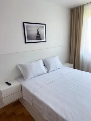 a bedroom with a white bed and a picture on the wall at DarViva Apartment Niš, center, private garage parking, river view in Niš