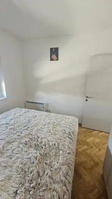 a white bedroom with a bed with a rug at Gudzic in Vrnjci