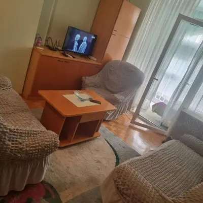 a living room with a table and chairs and a television at Apartman Mina in Vrnjačka Banja