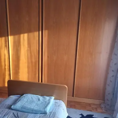 a bed in a bedroom with wooden cabinets at Apartman Mina in Vrnjačka Banja