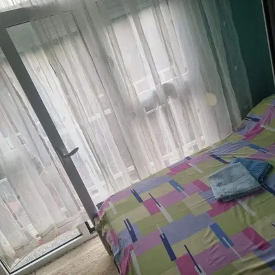 a bed in front of a window with curtains at Apartman Mina in Vrnjačka Banja