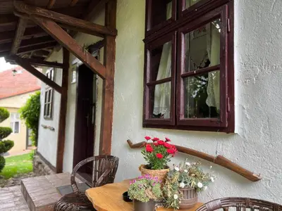 a wooden table with flowers on a porch with a window at Etno kuća Danica in Senje