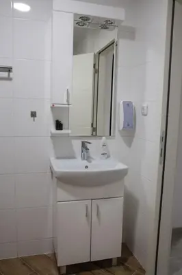 a white bathroom with a sink and a mirror at Apartmani Lepojevic in Prokuplje