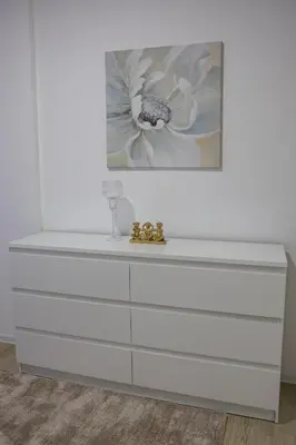 a white dresser with a flower painting on the wall at Apartmani Lepojevic in Prokuplje