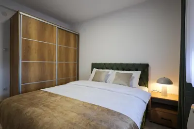 a bedroom with a large bed with a wooden headboard at Apartmani Lepojevic in Prokuplje
