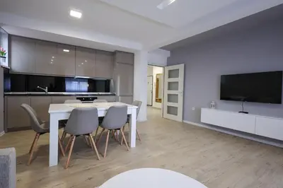 a kitchen with a white table and chairs and a tv at Apartmani Lepojevic in Prokuplje