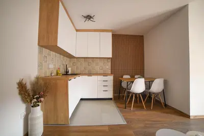 a kitchen with white cabinets and a table at Apartmani S in Vrnjačka Banja