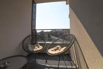two wicker chairs sitting on a balcony with a window at Apartmani S in Vrnjačka Banja