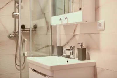 a white bathroom with a sink and a shower at Apartmani S in Vrnjačka Banja