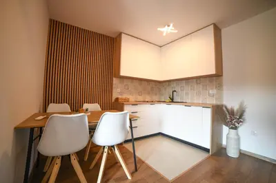 a kitchen with a wooden table and white chairs at Apartmani S in Vrnjačka Banja