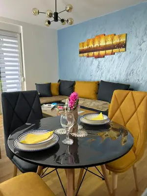 a dining room with a table and a couch at Ljubičica deluxe 2, sa dvorištem i parkingom in Vrnjačka Banja