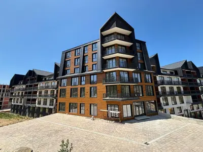 a large brick building in a parking lot at Raccoon Paradise Apartment Residence Hill B19 in Kopaonik
