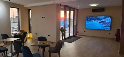 a waiting room with tables and chairs and a tv on the wall at SEE YOU Apartments in Niš