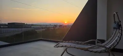 a bench sitting on a balcony looking out at the sunset at SEE YOU Apartments in Niš