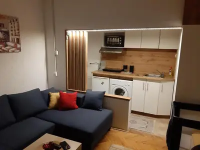 a living room with a blue couch and a kitchen at Ilić Sokobanja in Soko Banja