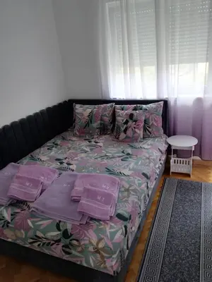 a bed in a room with pink sheets and pillows at Banjski kutak in Vrnjačka Banja