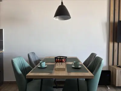 a dining room table with green chairs and a black lamp at Squirrel Viewpoint Apartment Residence Hill B124 in Kopaonik
