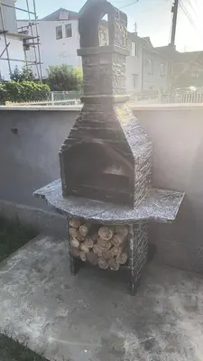 a stone outdoor stove with a pile of logs at TNT accommodation in Niš