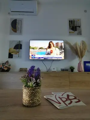 a living room with a tv and a table with flowers at Apartman Taris in Vrnjačka Banja