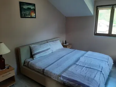 a bedroom with a bed with blue sheets and a window at Apartmani Miodragović - nedaleko od Snežnika, 100 metara pre bazena in Vrnjačka Banja