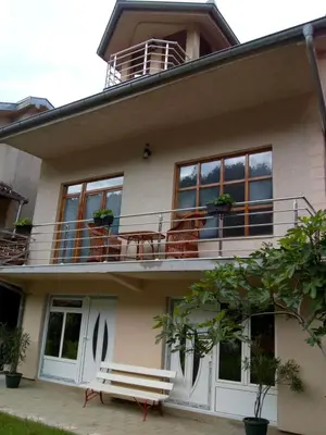 a house with a balcony with tables and chairs at Apartmani Miodragović - nedaleko od Snežnika, 100 metara pre bazena in Vrnjačka Banja