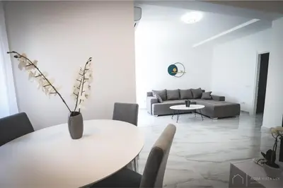 a white living room with a table and a couch at Aqua Vista Lux Raj in Vrnjačka Banja