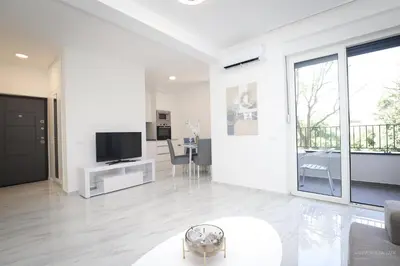 a white living room with a television and a table at Aqua Vista Lux Raj in Vrnjačka Banja