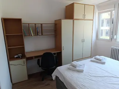 a bedroom with a bed and a desk and a chair at Eli's apartment in Niš